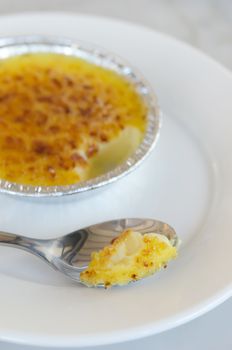close up caramelized custard with silver spoon ,  creme brulee