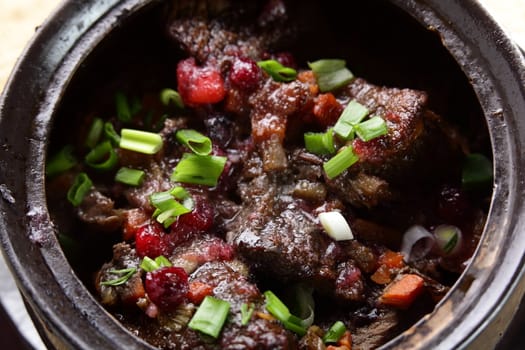 roated meat with onion and carrot on black pan