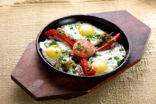 eggs with pepper and tomato on black pan