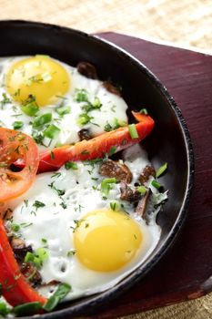 eggs with pepper and tomato on black pan