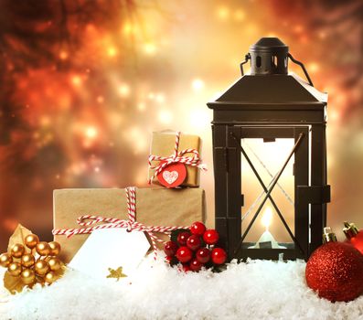 Christmas lantern with presents, ornaments and snow on a orange shinning night background