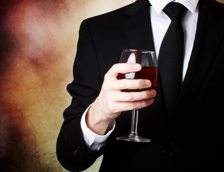 Elegant young man holding a glass of red wine 
