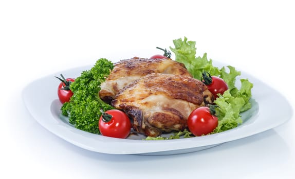 Fried chicken pieces on a plate with tomatoes, lettuce and parsley. Taken on a sheet of white plastic. Is not an isolate.