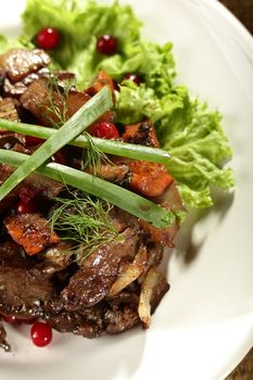 salad with meat and berries on the white dish