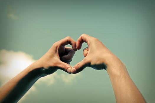 Toned Photo of Hands in Heart Shape on Sky Background