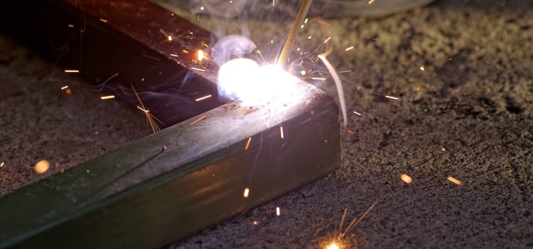 Iron welding with bright light and smoke at manufacturing