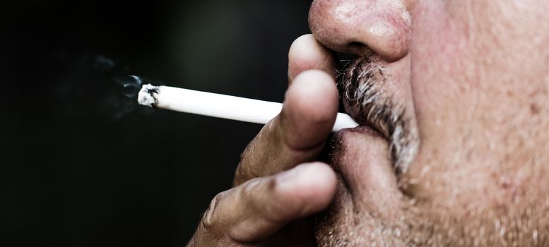 Smoking a cigarette against a dark background