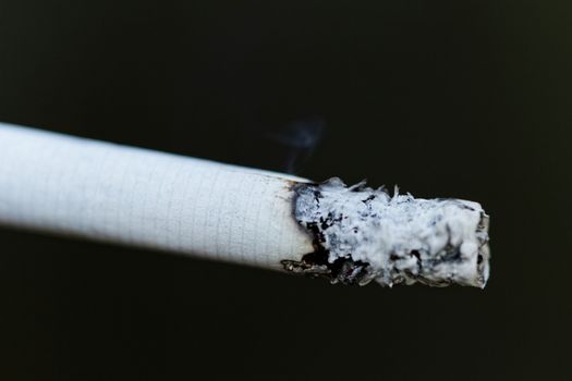 Smoking a cigarette against a dark background