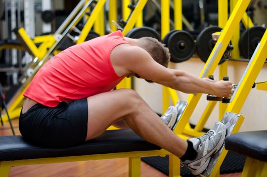 Attractive and fit young man in gym working out, doing pulley and exercising on equipment