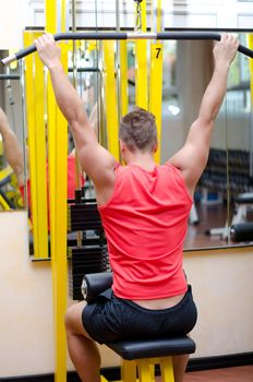 Attractive and fit young man in gym working out and exercising on equipment