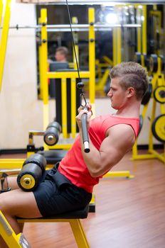 Attractive and fit young man in gym working out and exercising on equipment