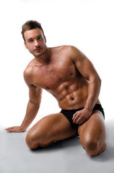 Handsome, fit, young man on his knees showing muscular naked body