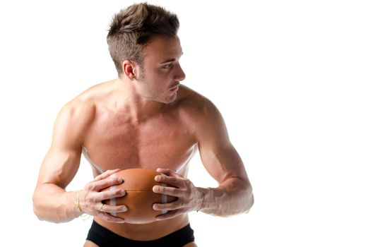 Handsome, serious young man shirtless, holding american football ball in his hands