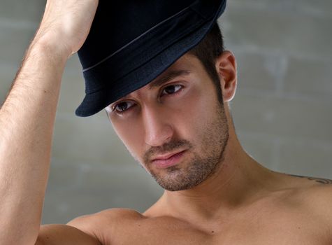 Head-shot of attractive shirtless young man wearing hat, looking off camera