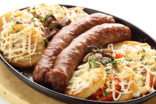 hot roasted sausages with potato on black pan