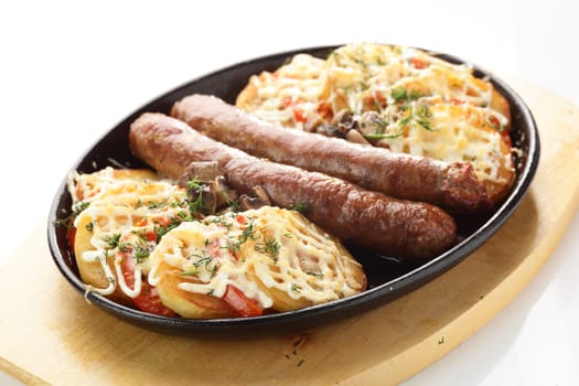 hot roasted sausages with potato on black pan