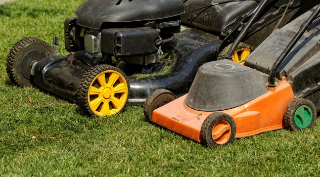 two lawnmower in the garden lawn the grass (fuel and electricity)