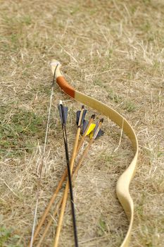 color archery arrows and bow in nature on the ground