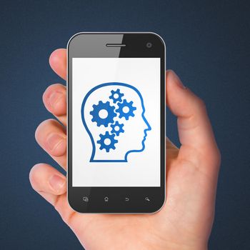Advertising concept: hand holding smartphone with Head With Gears on display. Generic mobile smart phone in hand on Dark Blue background.