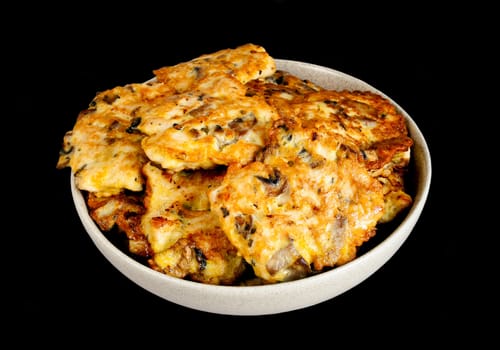 Cutlets from chicken, mushrooms and eggs in ceramic bowl isolated on black