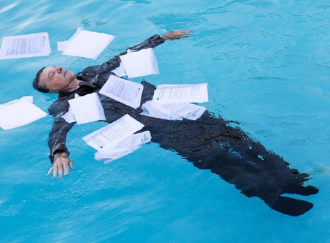 Senior caucasian businessman in suit sinking underwater in deep blue pool worried about being underwater with mortgage payments