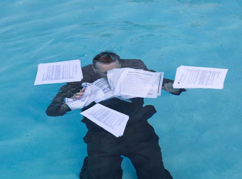 Senior caucasian businessman in suit sinking underwater in deep blue pool worried about being underwater with mortgage payments