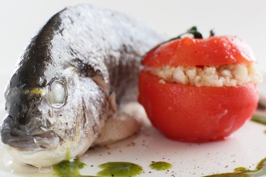 tasty boiled big fish with tomato on white dish