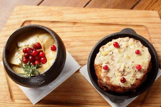 two black pots with hot pancakes on wooden table