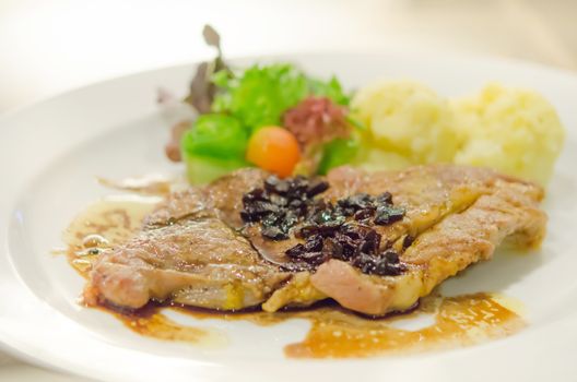 roasted pork steak served with mashed potato and fresh vegetable