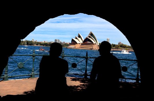 Bradfield Park, Sydney Australia - October 6, 2013:  Silhouette of man and woman enjoying Sydney Harbour and Opera House views from a stone arch shelter in Bradfield Park.