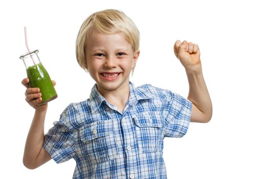 A cute boy holding a bottle of green smoothie or juice is flexing his muscles and smiling. Isolated on white.