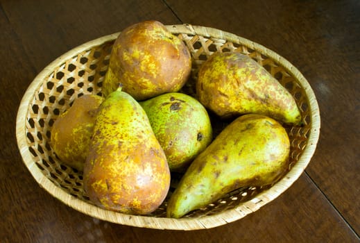 Ripe fresh pears in wicker bowl