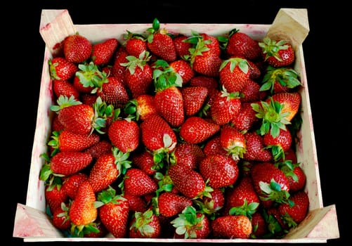 Strawberry in wooden box over black background