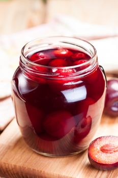 Appetizing plum compote in glass jar close up.