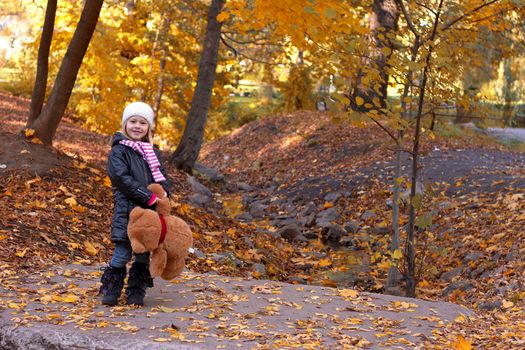 Adorable girl with teddy bear outdoors on beautiful autumn day