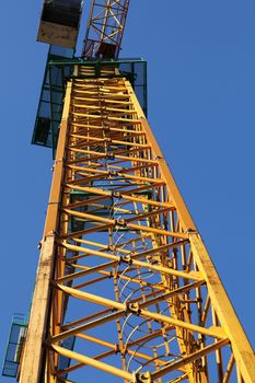 part of yellow construction crane against blue sky, industrial element