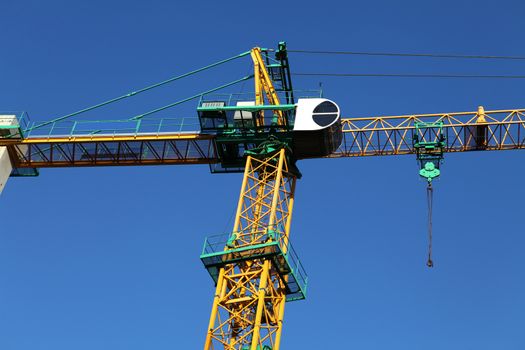 yellow construction crane against blue sky, industrial element