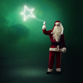 Santa Claus is holding a shining star sign on a string