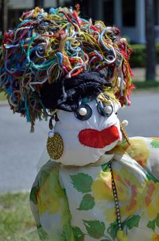 A fall scarecrow with earrings, red lips, and spaghetti-like yarn hair