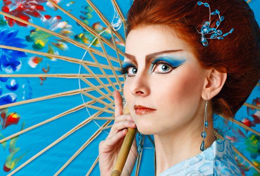 Attractive geisha in a smart dress with an umbrella, photographed in the studio