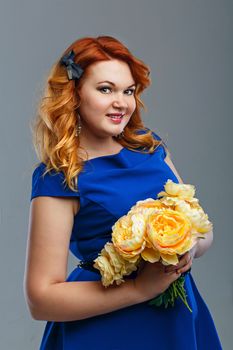 Attractive red-haired girl holding a bouquet of yellow flowers