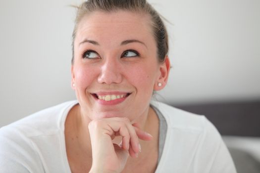 Beautiful smiling woman daydreaming looking up into the air as she recalls happy memories