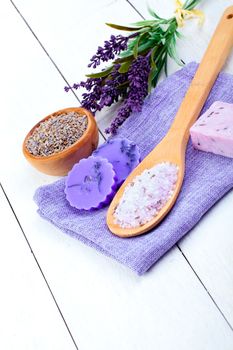 lavender flowers, bath salt and candle on white wooden background