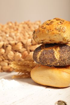 Assorted rolls in a bakery stacked on top of one another including a crisp crusty golden roll, a poppy seed roll and one topped with delicious roasted sunflower seeds