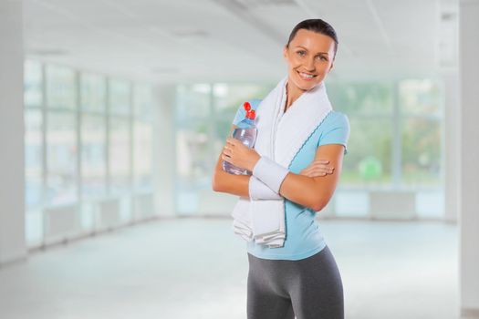 beautiful fitness girl with towel and bottle of water smiling