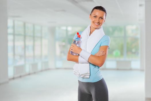 beautiful fitness girl with towel and bottle of water smiling