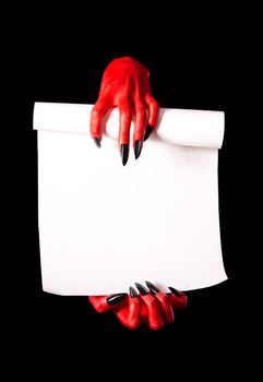 Red devil hands holding paper scroll for deal with devil concept, isolated on black background 