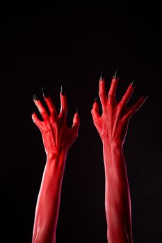 Red demonic hands with black nails, Halloween theme, studio shot on black background 