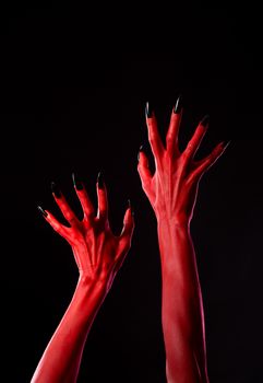 Spooky red demonic hands with black nails, Halloween theme, studio shot 