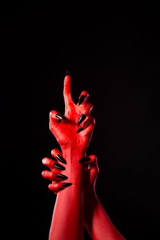 Scary red demonic hands with black nails, Halloween theme, studio shot 